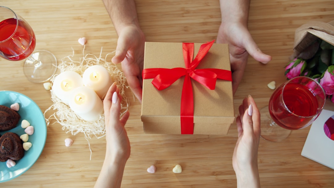 Hände überreichen ein Geschenk mit roter Schleife